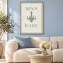Maison Bohème – Groene Kroonluchter en Blauwe Letters in een rustige woonkamer met lichtblauwe wand, crème bouclé bank, travertin bijzettafel en dunne zwarte lijst