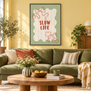 Slow Life – Rode Strikken en Zachte Strepen in een vrolijke woonkamer met zachtgele muur, olijfgroene bank, houten salontafel en dunne zwarte lijst