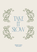 Take It Slow – Groene Bloemen en Blauwe Letters – Groene bloemen omlijsten blauwe Take It Slow letters op een lichte achtergrond.