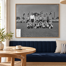 Ingelijste PSV-elftalfoto uit 1956 boven een blauwe bank in een lichte eethoek.
