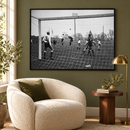 PSV–Heracles-foto uit 1964 in een zwarte lijst boven een lichte fauteuil tegen een olijfgroene muur.