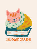Roze slapende kat met groene sjaal en gele deken op een blauw boek met tekst Snuggle Season tegen crème