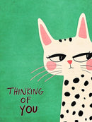 Een crèmekleurige kat met zwarte vlekken en roze details op groen, met de tekst Thinking of You.